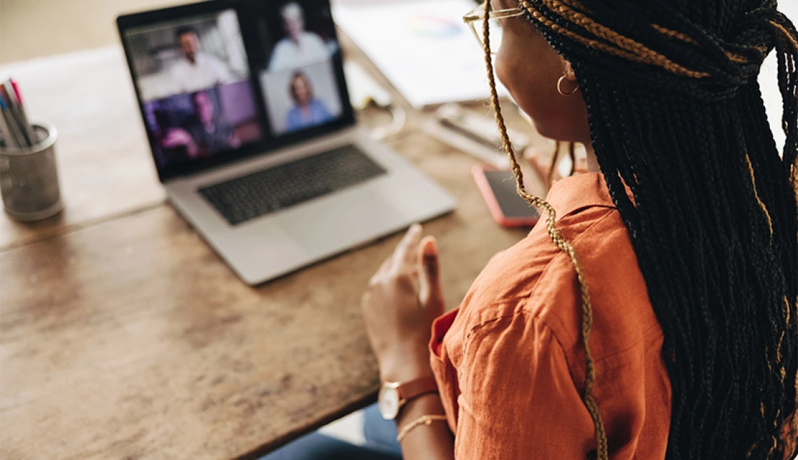 Over-the-shoulder shot of person on a zoom call on laptop