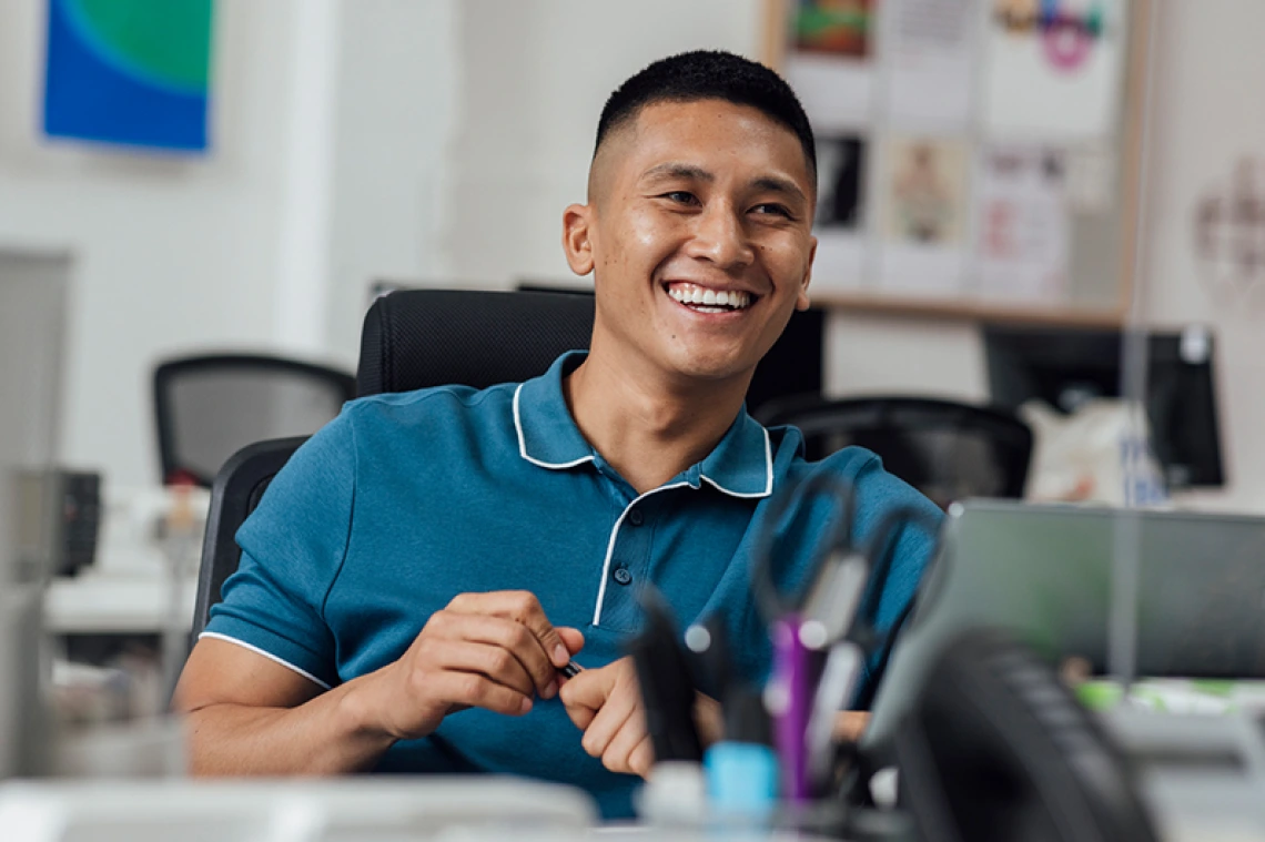 Person wearing blue collared shirt smiling in classroom setting