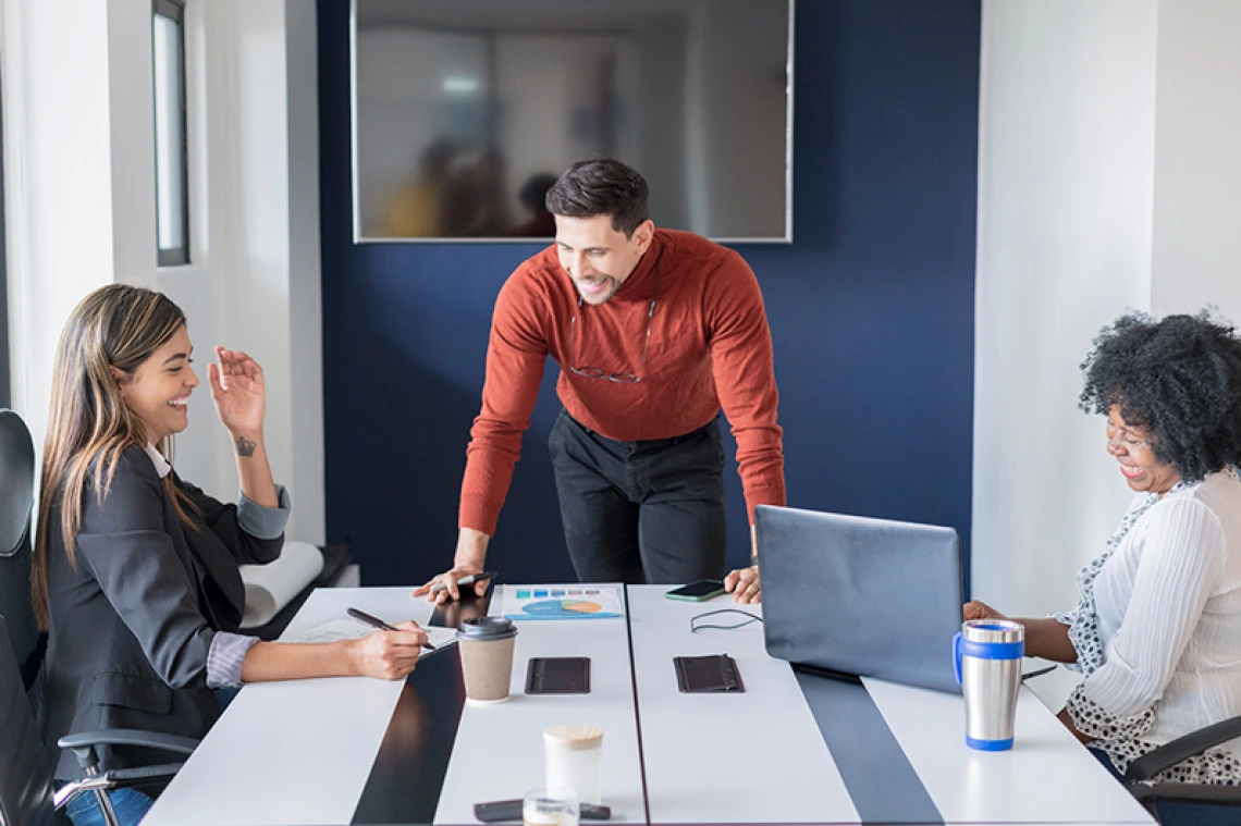 Three people sitting around a table joyfully working together