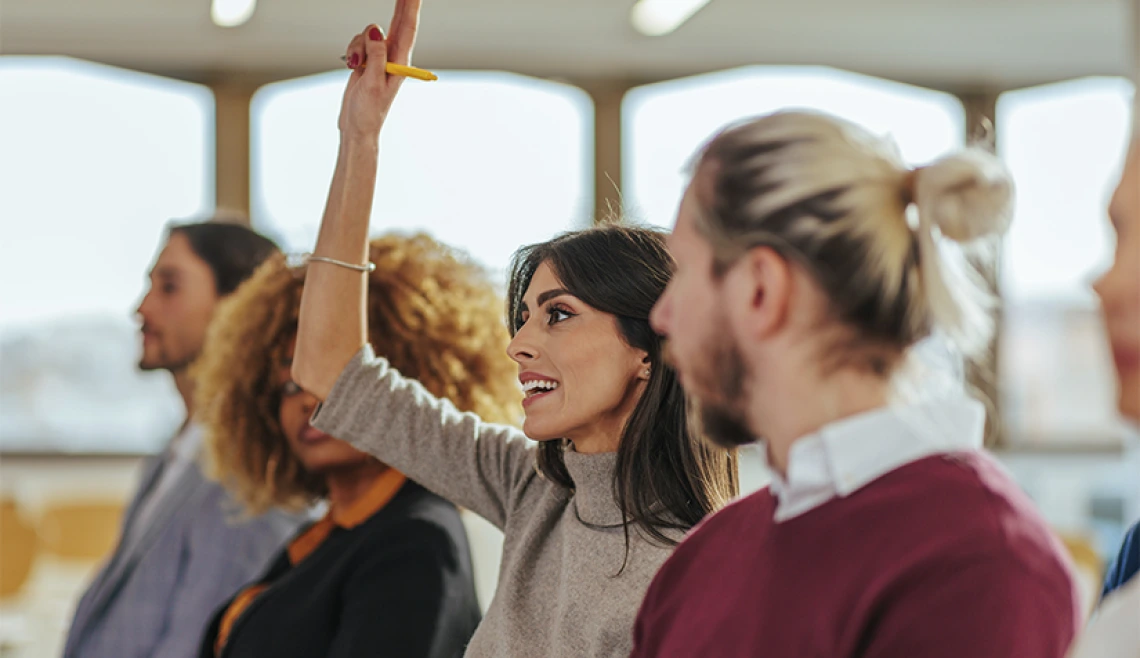 Person raising their hand inside a conference room