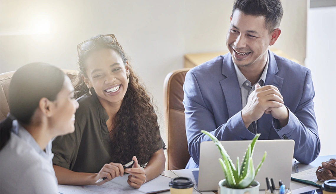 Group of working professionals talking and laughing at desk