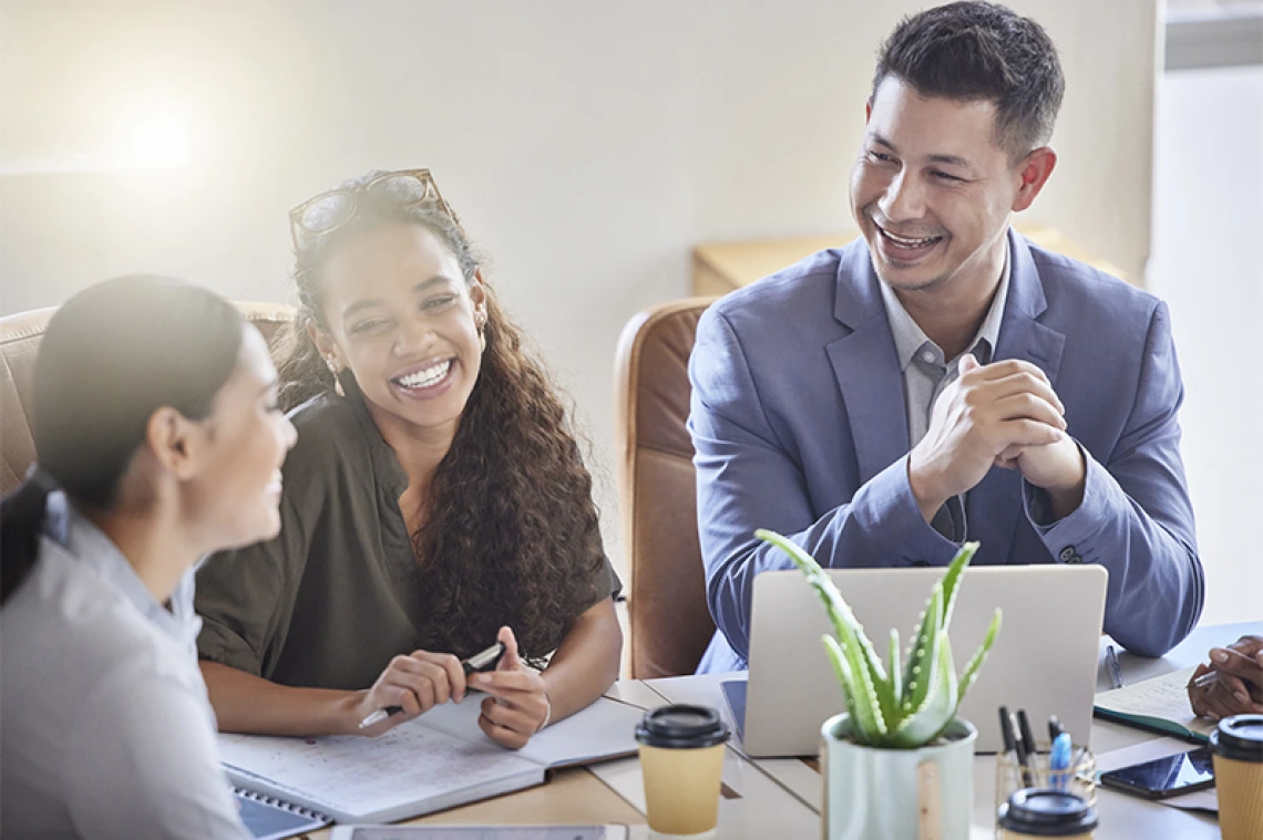 Group of working professionals talking and laughing at desk