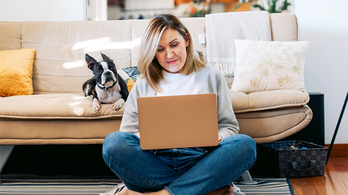 Person sitting on laptop on the floor in front of couch