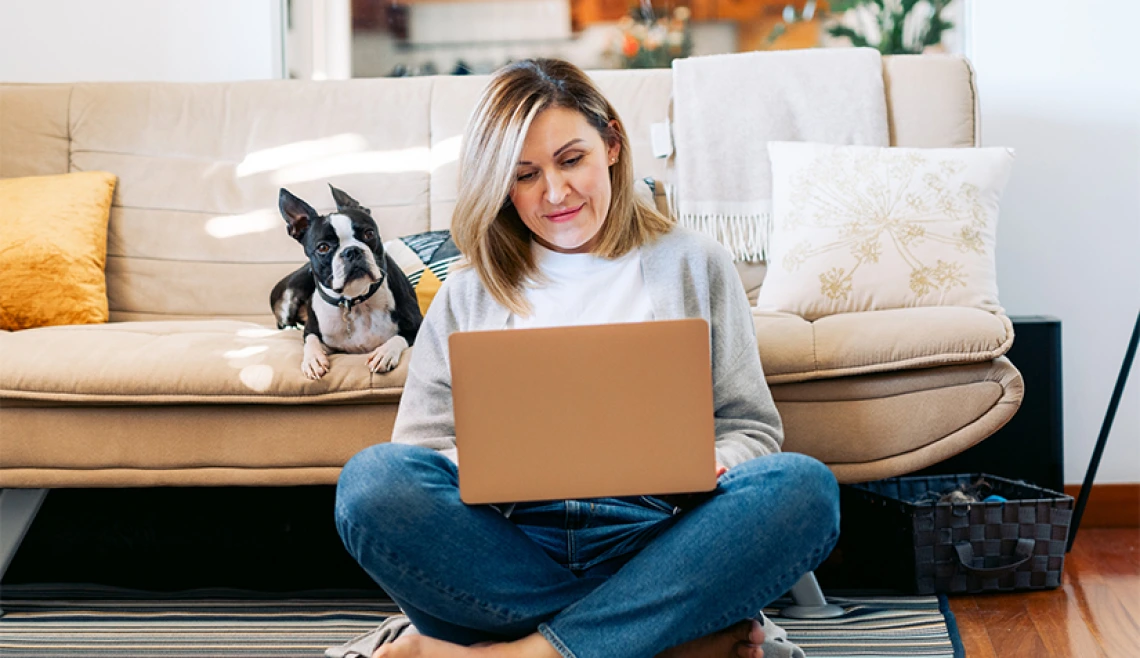 Person sitting on laptop on the floor in front of couch