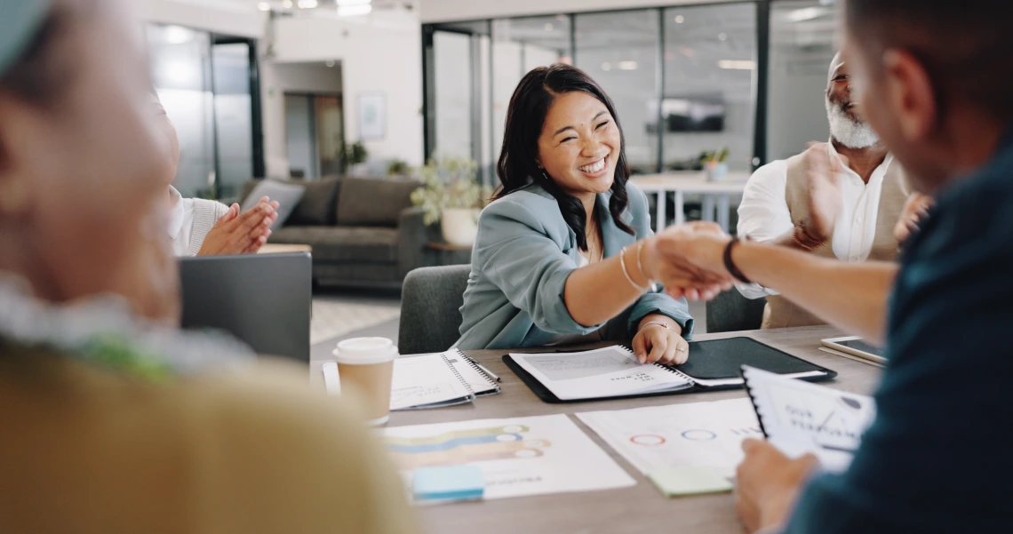 Woman shaking hands with colleagues across a table