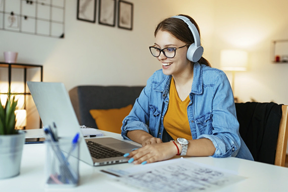 Smiling student wearing headphones and working on laptop