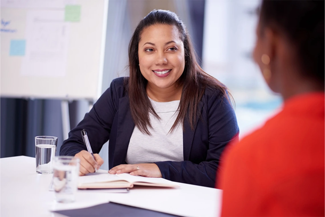 Smiling businessperson working at desk with another person
