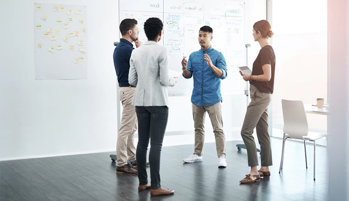 Group of working professionals talking in front of a white board