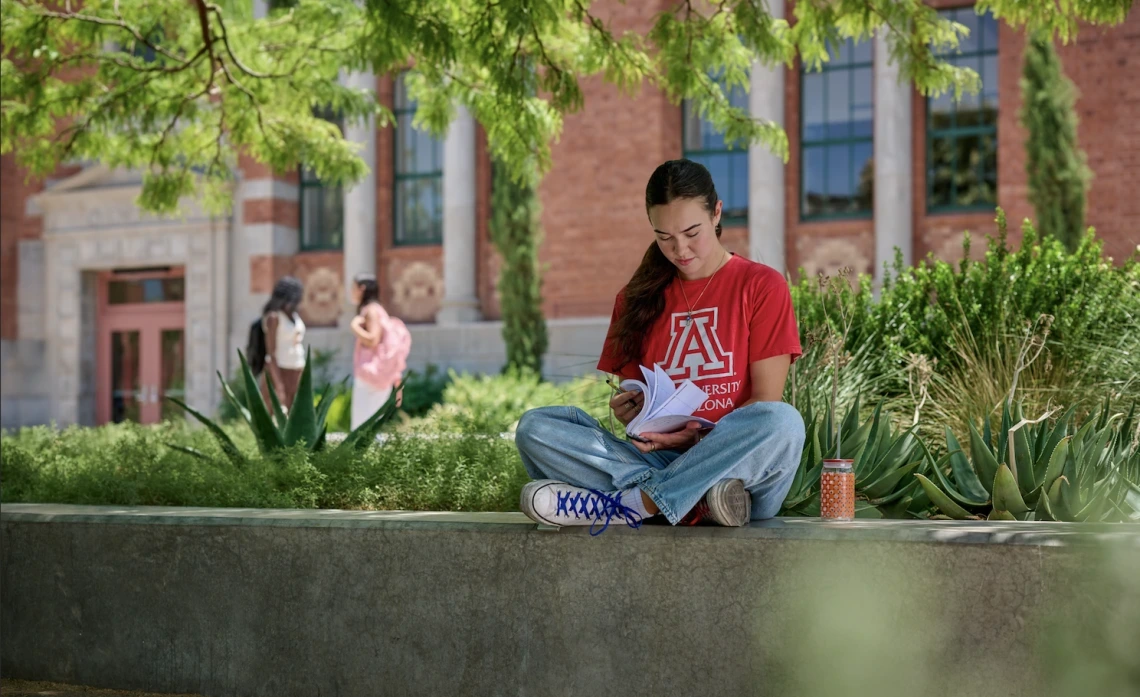 Student in red U of A t-shirt flipping through a book